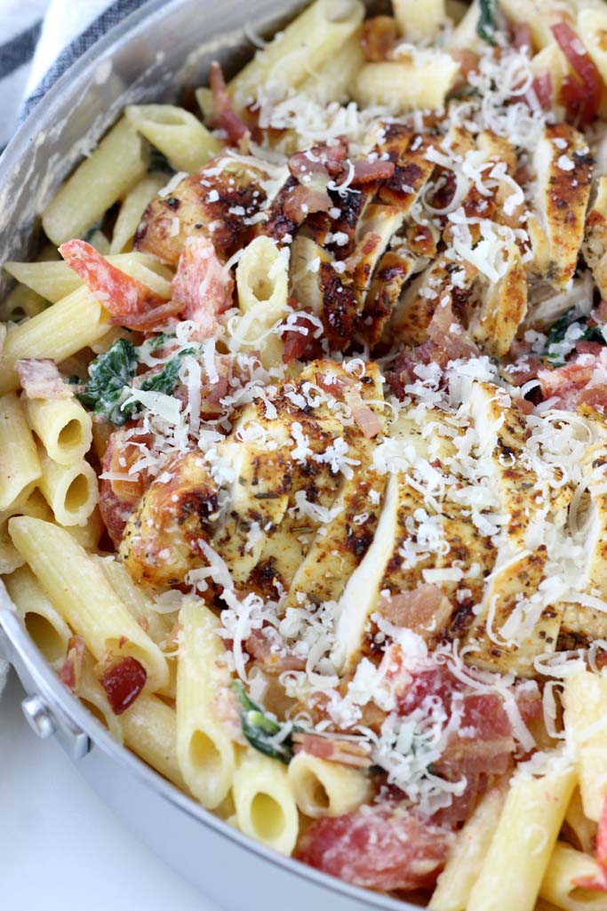 Easy Chicken & Bacon Pasta with Spinach and Tomatoes is quick and delicious. Seasoned chicken, crispy bacon, fresh spinach and tomatoes take this weeknight recipe to the next level!