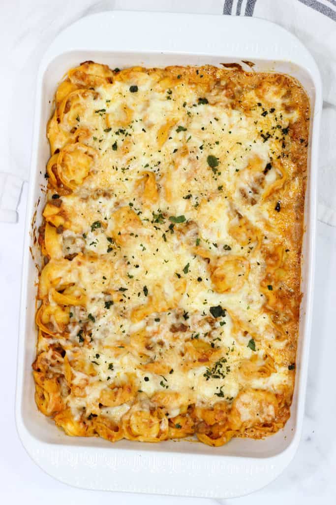 melted cheese on top of tortellini pasta baked in a casserole dish.